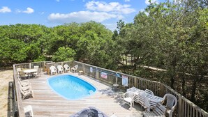 A wooden deck with a swimming pool, lounge chairs, and a wooden fence. - Ola Corolla -- Pet Friendly Oceanside home with Pool, Hot Tub (Corolla)
