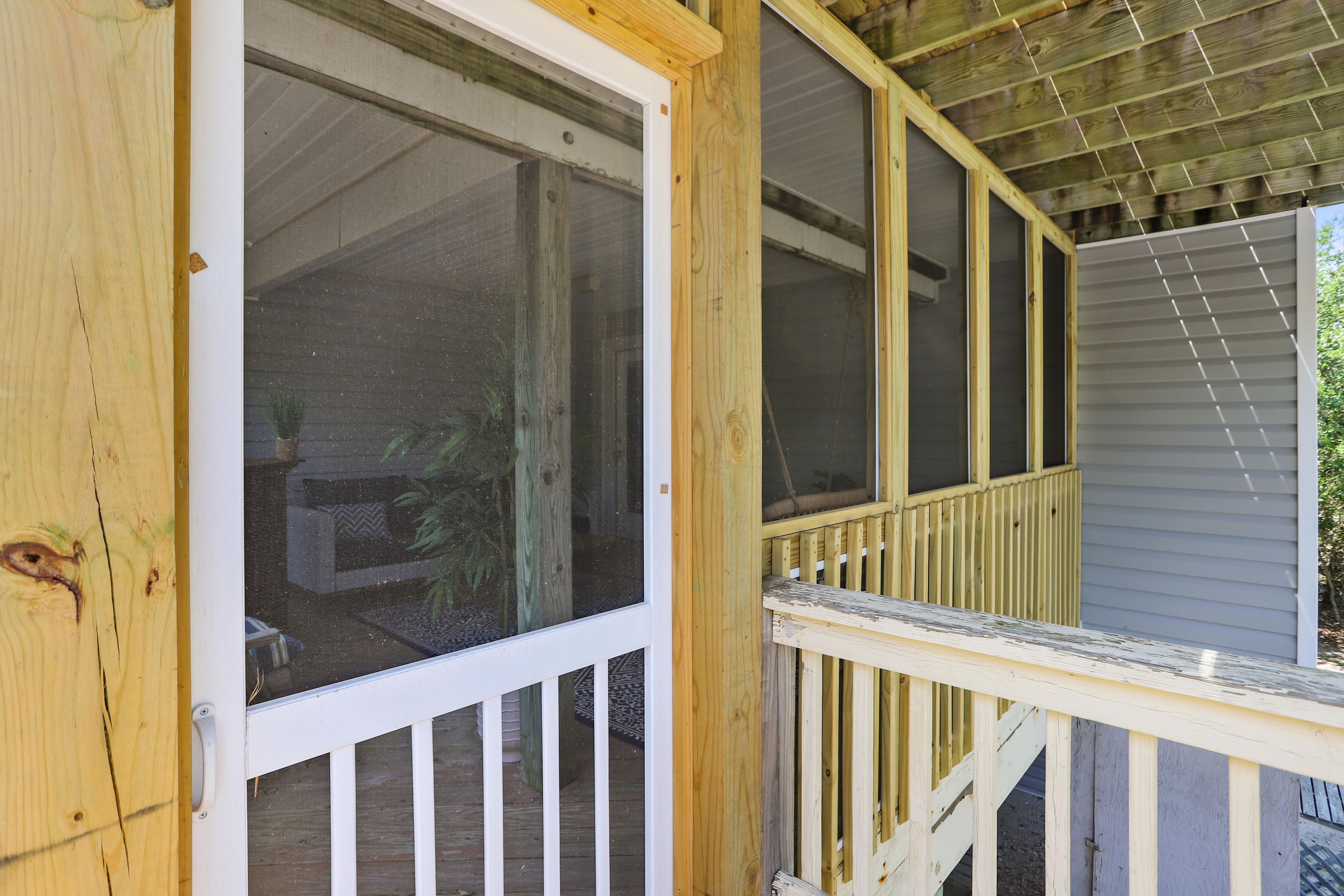 A wooden porch with a white railing and a screened window.