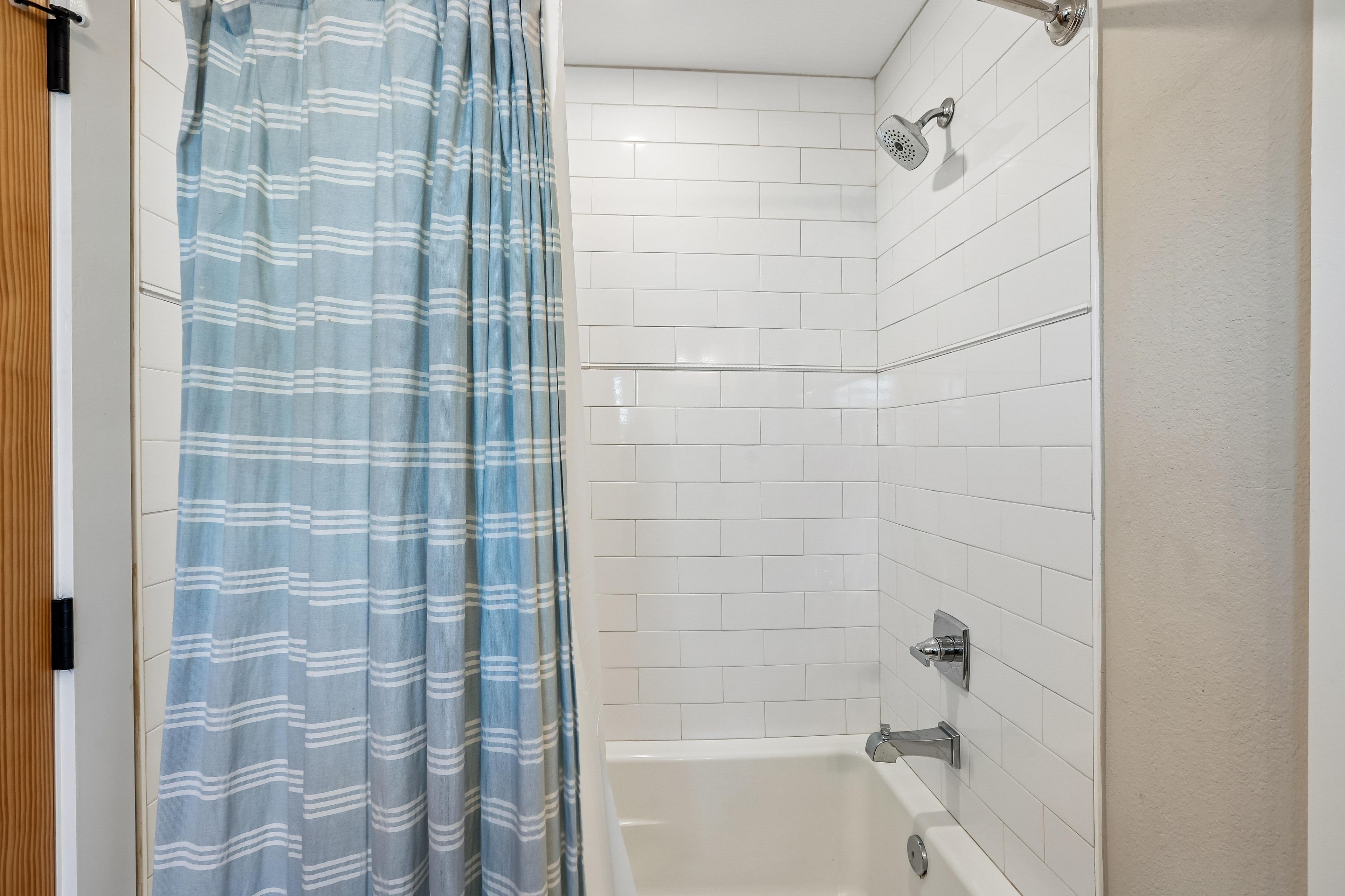 A bathroom with a shower, a bathtub, and a curtain.