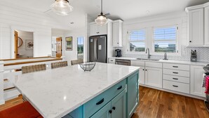 A modern kitchen with white cabinetry, a large marble island, and a view of the outdoors.