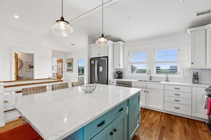 Una cocina moderna con armarios blancos, una isla grande de mármol y vistas al exterior.
