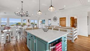 A spacious kitchen with a large island, white cabinetry, and a view of the ocean.
