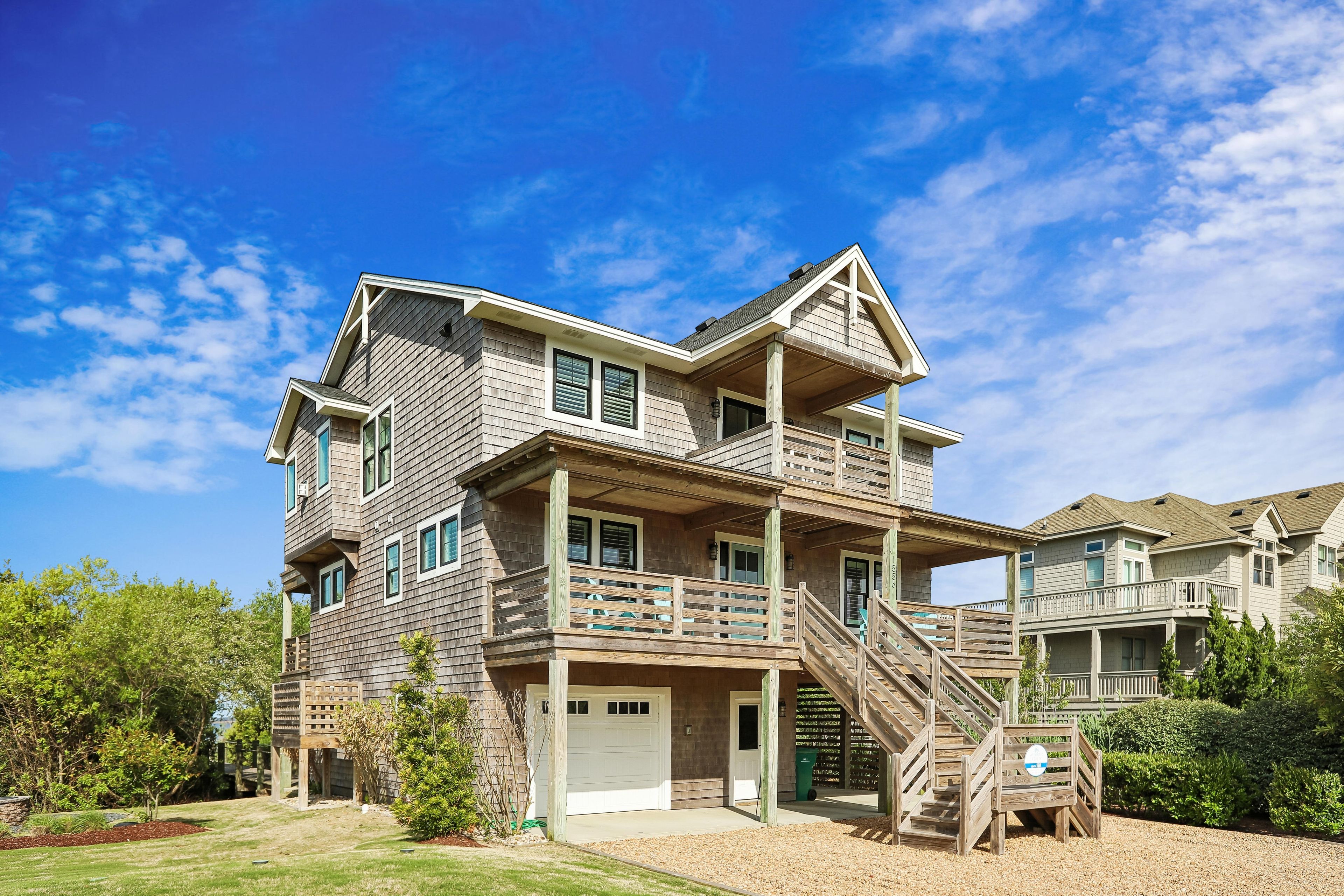 A multi-story house with a front deck and a staircase leading to the second floor.