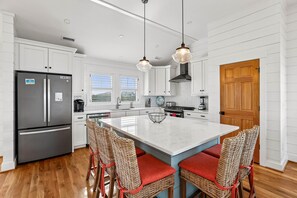 A modern kitchen with white cabinetry, a central island, and a built-in stove. - Sanctuary -- Soundfront Beauty with Private Pier and beach 300 feet away! (Duck)