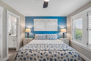 A bedroom with a bed, two bedside tables, a nightstand, a dresser, and a window with blinds.