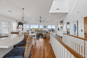 A spacious living area with a large dining table, comfortable seating, and a view of the outdoors. - Knot for Sail -- Newer Soundfront Home with Hot Tub and Firepit (Duck)