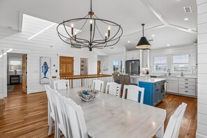 Una cocina moderna con armarios blancos, una isla central y una lámpara de araña.