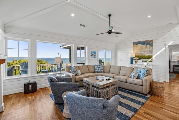 A spacious living room with a large sectional sofa, a coffee table, and a view of the ocean.