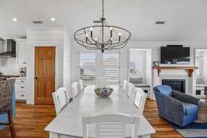 A modern kitchen with white cabinetry, a wooden door, and a coffee maker on the counter.
