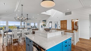 Un'ampia cucina con un'isola grande, pavimento in legno e vista mare.