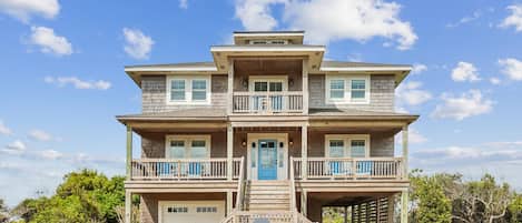 A multi-story house with a covered front porch, a garage, and a well-maintained lawn.