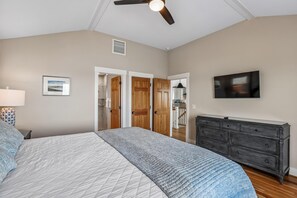 Une chambre à coucher comprenant un lit, une commode, un ventilateur de plafond et un téléviseur.
