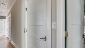 Un pasillo con puertas blancas, algunas con manijas y otras con cerraduras.