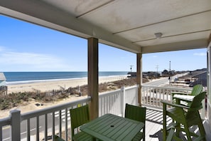 A covered outdoor area with a view of the beach, a table, and green chairs. - Fantasea -- Spectacular Semi OF Home in Kitty Hawk w/Elevator, Pool and Ocean Views (Kitty Hawk)