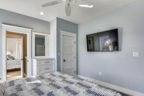 A bedroom with a bed, a TV mounted on the wall, a ceiling fan, and a door leading to another room. - Fantasea -- Spectacular Semi OF Home in Kitty Hawk w/Elevator, Pool and Ocean Views (Kitty Hawk)