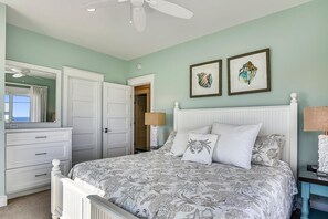 Ein Schlafzimmer mit einem Bett, einem Schminktisch, einem Spiegel und zwei gerahmten Bildern an der Wand.
