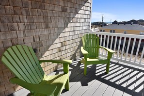 Two green Adirondack chairs on a wooden deck with a white railing, overlooking a residential area with houses and a clear sky. - Fantasea -- Spectacular Semi OF Home in Kitty Hawk w/Elevator, Pool and Ocean Views (Kitty Hawk)
