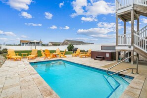 A swimming pool with a wooden deck, surrounded by yellow Adirondack chairs, and a hot tub area. - Fantasea -- Spectacular Semi OF Home in Kitty Hawk w/Elevator, Pool and Ocean Views (Kitty Hawk)