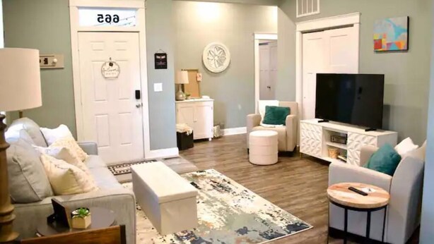 A living room with a sofa, ottoman, coffee table, TV, and a rug. - The Dragonfly- A Historic Gem with Hot Tub (Franklin)