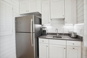 Eine moderne Küche mit weißen Schränken, einem Edelstahlkühlschrank, einer Kaffeemaschine und einem Toaster.