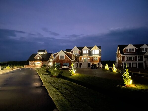 A large, multi-story residential building with a driveway and well-lit landscaping.