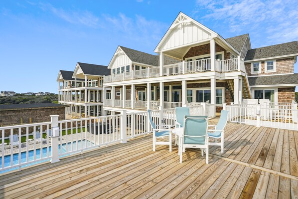 A multi-story house with a wooden deck and a pool.