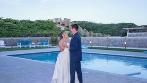 A couple dancing by a pool with a wooden deck and chairs in the background. - Austin -- New Construction Oceanfront 11BR with Elevator, Fire Pit, Pool, Fitness Room and More! (Corolla)