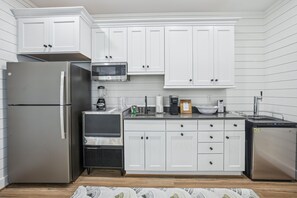A modern kitchen with white cabinetry, stainless steel appliances, and a built-in microwave. - Newbern - New Cons. Semi Oceanfront in Corolla with Fire Pit, Elevator, Hot Tub and More! (Corolla)