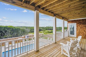 A wooden deck with a pool, white chairs, and a view of a natural landscape. - Newbern - New Cons. Semi Oceanfront in Corolla with Fire Pit, Elevator, Hot Tub and More! (Corolla)