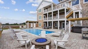 A two-story building with a swimming pool, outdoor seating, and a fire pit. - Newbern - New Cons. Semi Oceanfront in Corolla with Fire Pit, Elevator, Hot Tub and More! (Corolla)