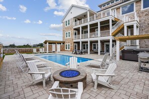 A two-story building with a swimming pool, outdoor seating, and a fire pit. - Newbern - New Cons. Semi Oceanfront in Corolla with Fire Pit, Elevator, Hot Tub and More! (Corolla)