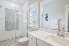 A modern bathroom with a glass-enclosed shower, a white toilet, a vanity with a sink, and a large mirror. - Newbern - New Cons. Semi Oceanfront in Corolla with Fire Pit, Elevator, Hot Tub and More! (Corolla)