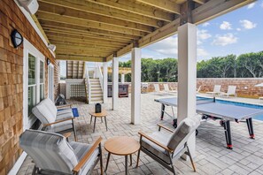 An outdoor patio area with a ping pong table, lounge chairs, and a pool. - Newbern - New Cons. Semi Oceanfront in Corolla with Fire Pit, Elevator, Hot Tub and More! (Corolla)
