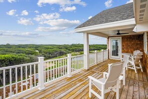 A wooden deck with white railings, a covered area with a door, and outdoor furniture. - Newbern - New Cons. Semi Oceanfront in Corolla with Fire Pit, Elevator, Hot Tub and More! (Corolla)