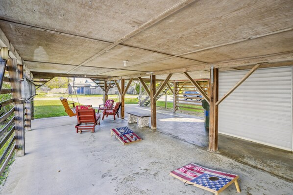 Un espacio al aire libre techado, con suelo de hormigón, bancos de madera y una mesa.