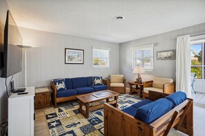 A living room with a sofa, armchairs, a coffee table, and a TV.