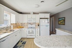 A modern kitchen with white cabinetry, a microwave, an oven, and a refrigerator.
