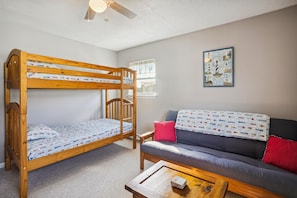 Una cama litera con un colchón estampado, un sofá con una manta decorativa y un cuadro en la pared.