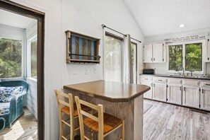 A kitchen with a bar area, wooden cabinets, and a view of the outdoors. - House of Friends -- New Listing!  Private Pool, Easy Beach Access (Kitty Hawk)