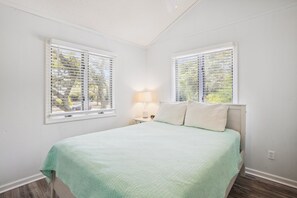 A bedroom with a bed, two windows, a nightstand, and a lamp. - House of Friends -- New Listing!  Private Pool, Easy Beach Access (Kitty Hawk)