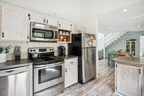 A modern kitchen with stainless steel appliances, wooden cabinets, and a built-in oven. - House of Friends -- New Listing!  Private Pool, Easy Beach Access (Kitty Hawk)