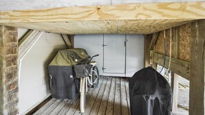 Et lille, lukket rum med en cykel, opbevaringsposer, trægulv og en dør med lås.