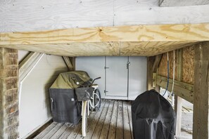 Ein kleiner, abgeschlossener Raum mit einem Fahrrad, Gepäckbeuteln, Holzboden und einer verschließbaren Tür.