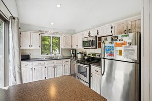A kitchen with white cabinets, a stainless steel refrigerator, a microwave, and a stove.