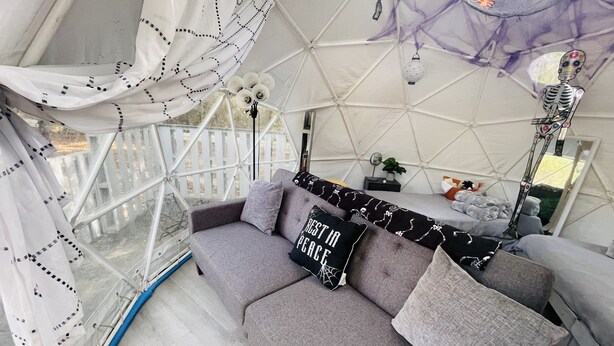 A cozy interior with a grey sofa, patterned cushions, and a small table with decorative items.