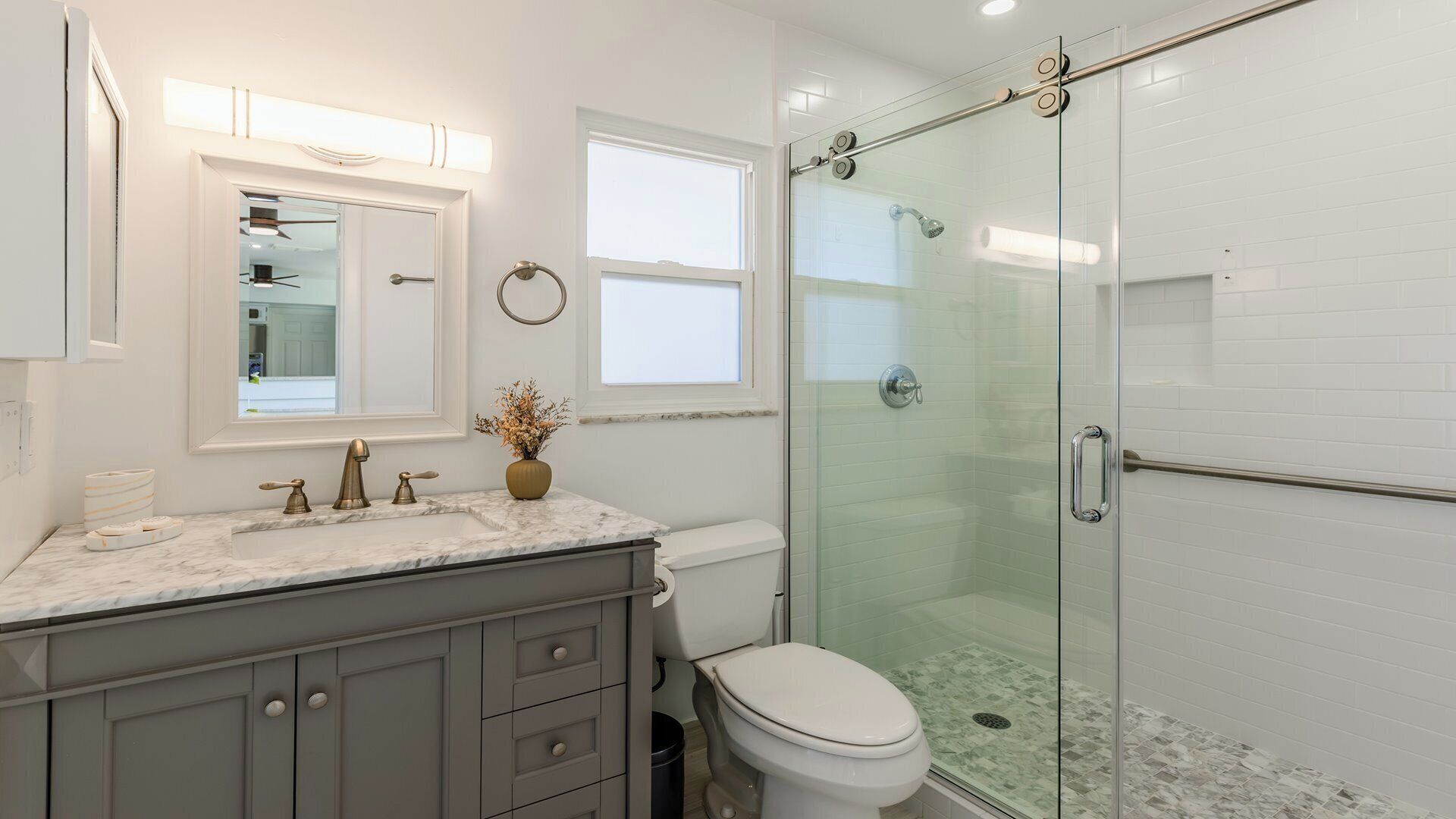 A modern bathroom with a glass shower enclosure, a marble sink, and a toilet.