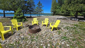 Järvenrantainen oleskelualue, jossa on neljä keltaista Adirondack-tuolia aseteltuna nuotiopaikan ympärille.