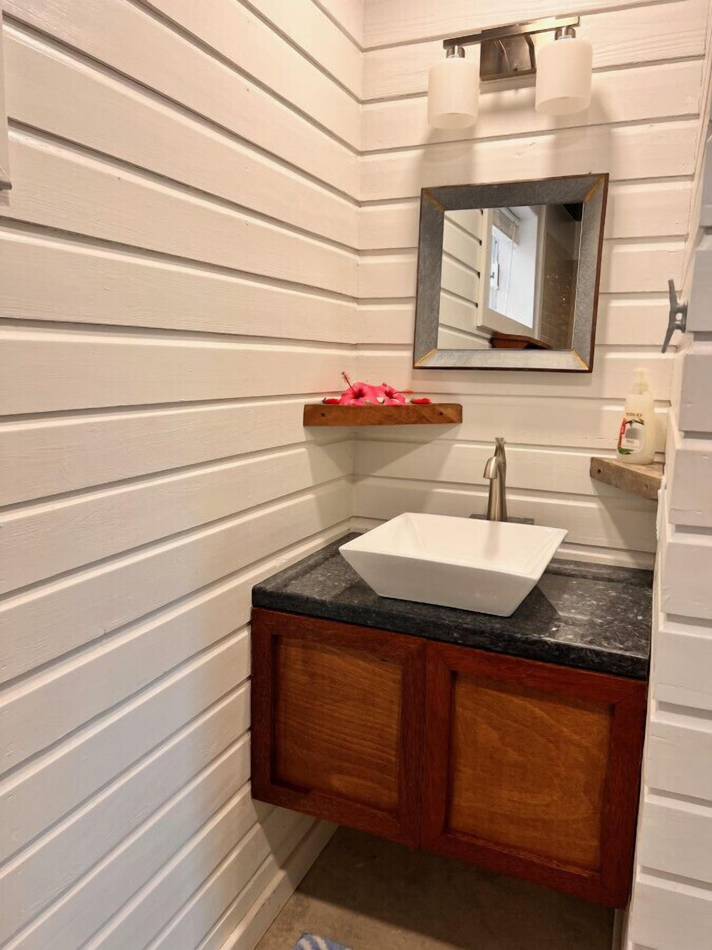 A bathroom with a white sink, wooden cabinets, and a mirror above the sink.