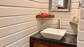 A bathroom with a white sink, wooden cabinets, and a mirror above the sink.