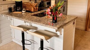 Una cocina con una isla central, taburetes de bar, un refrigerador y un microondas.